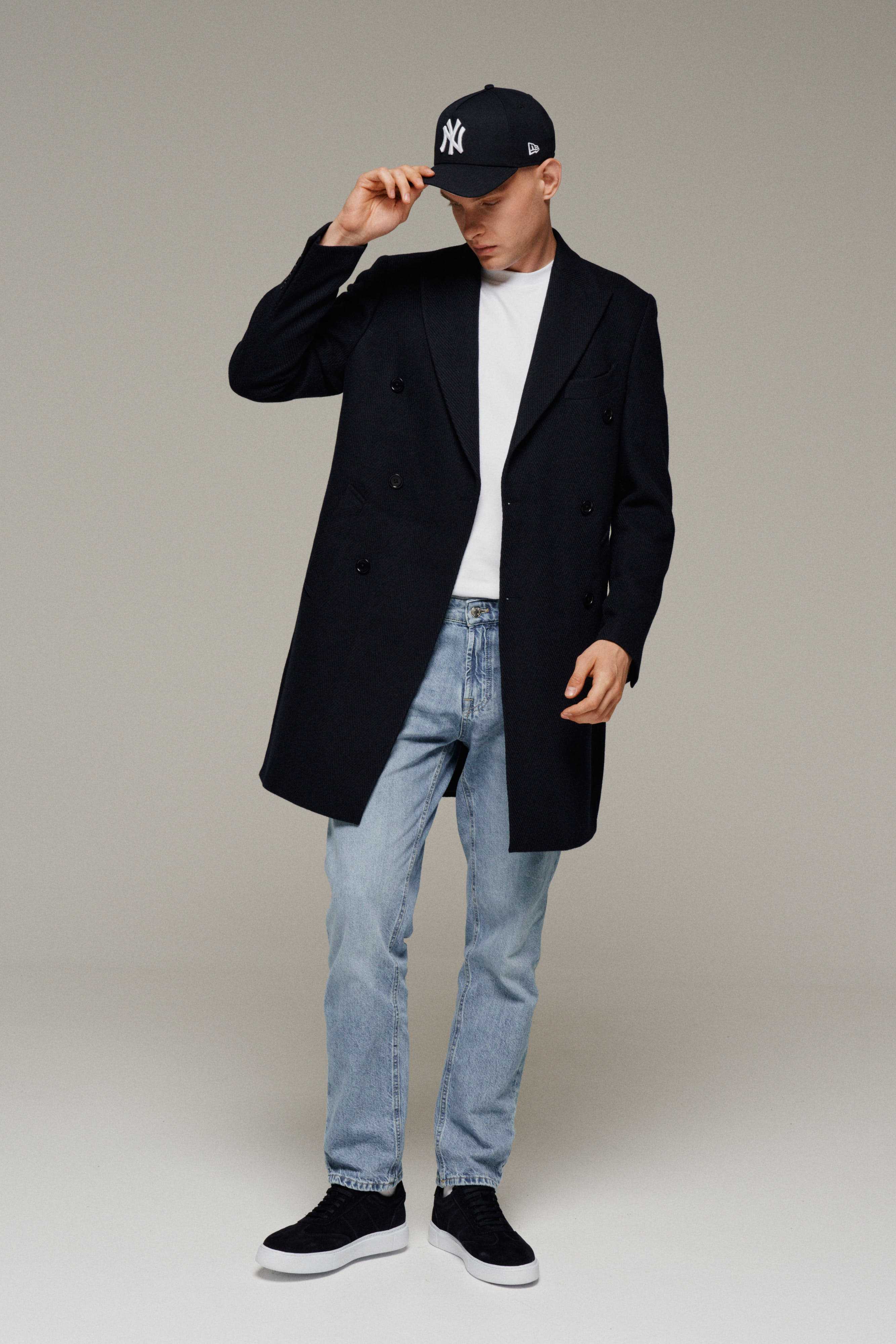 Мужчина в молодежном пальто и джинсах