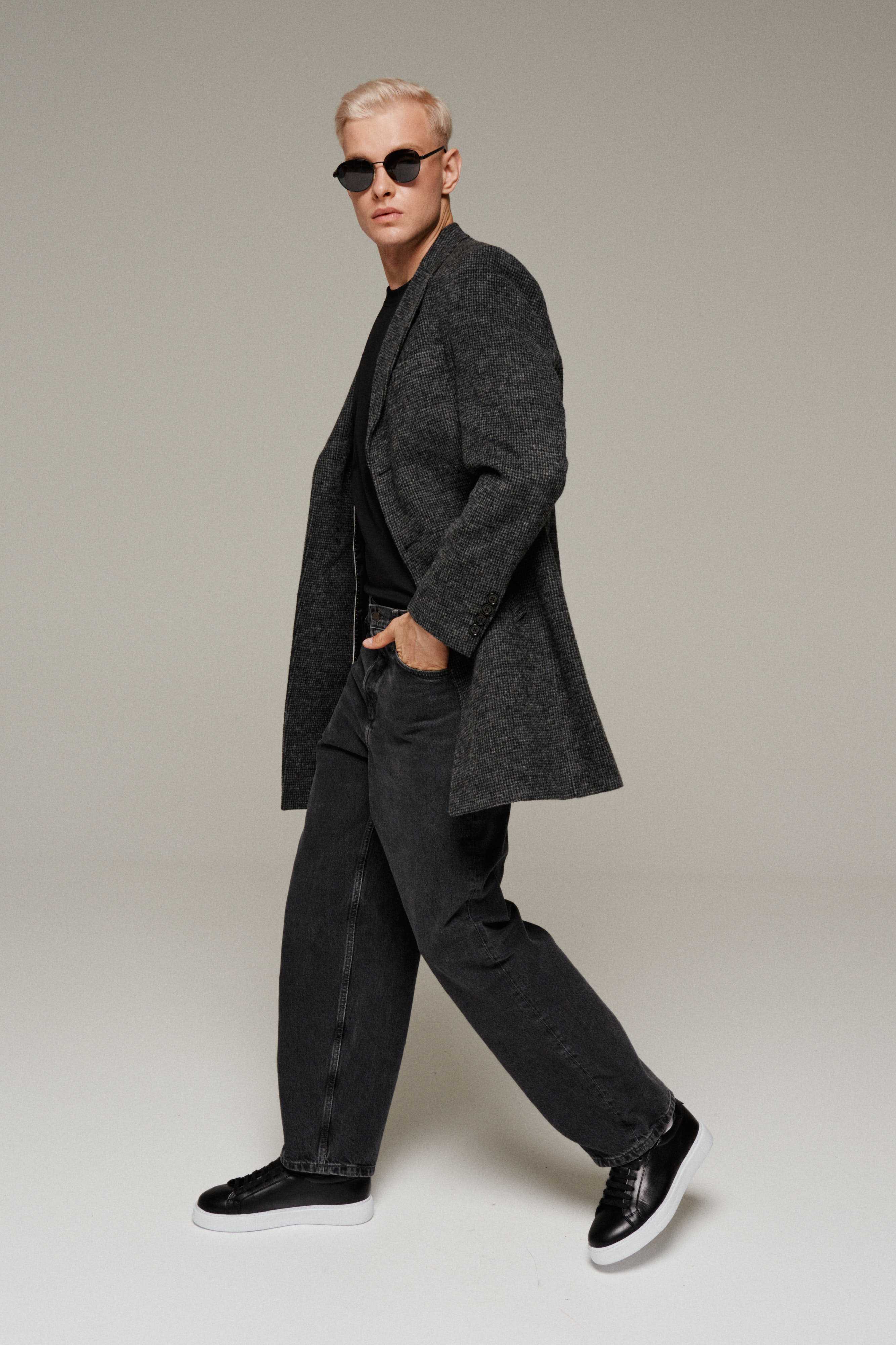 Мужчина в молодежном пальто, джинсах и кроссовках